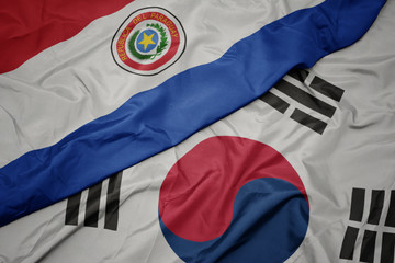 waving colorful flag of south korea and national flag of paraguay.