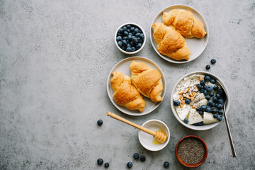 Breakfast table with croissants, yogurt or cottage cheese, berries, nuts and chia seeds. Top view.  Copy space