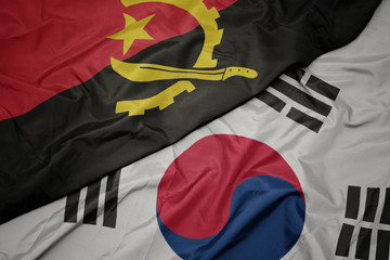 waving colorful flag of south korea and national flag of angola.