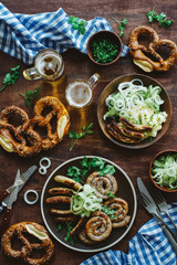 Traditional german appetizer and beer glasses on dark brown wooden table. Mashed potatoes, salad, pretzels and sausages. Oktoberfest party background