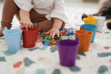 Toddler girl plays with beads and multicolored - obrazy, fototapety, plakaty