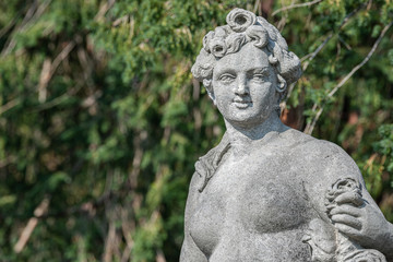 Fototapeta na wymiar Old statue of a sensual naked Renaissance era woman during bathing in park of Potsdam, Germany