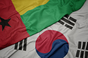 waving colorful flag of south korea and national flag of guinea bissau.