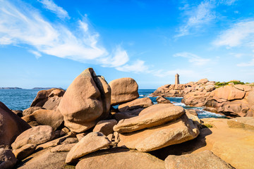 The Ploumanac'h lighthouse, named Mean Ruz, on the Pink Granite Coast in northern Brittany on the municipality of Perros-Guirec, France, with large pink granite rocks in the foreground.
