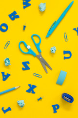 Blue school supplies on a yellow desk.Back to school background