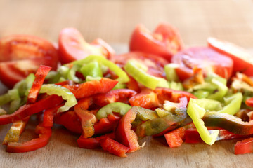 many slices of pepper and tomato on a cutting board front view. prepare a fresh salad of vegetables