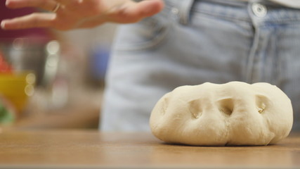 woman on the kitchen table makes domestic food pizza, hands work and pushing stir knead the dough, selective focus dolly shot