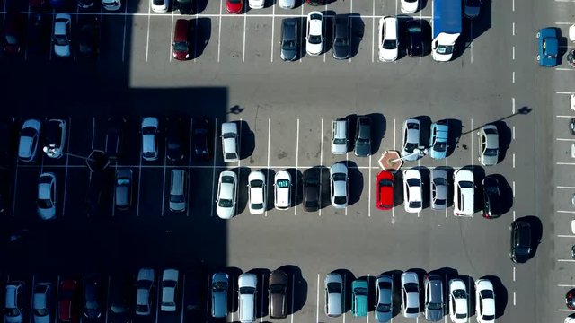 A view from above to the process of car parking. Heavy traffic in the parking lot. Searching for spaces in the busy car park. Parking advice. Cruising for parking in busy business center