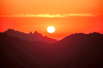 Sun over mountain ridges; beautiful colorful mountain sunset