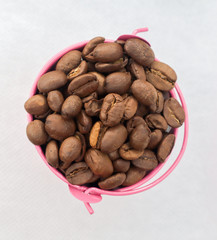 Heap coffee beans in pink bucket on white background