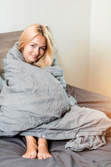 Positive woman sitting in bed at home