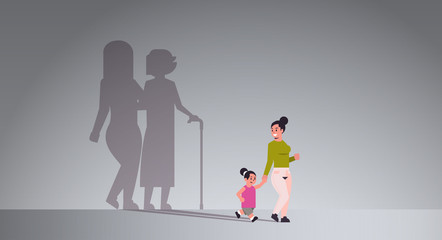 Fototapeta premium mother with daughter holding hands shadow of young and mature woman standing together imagination aspiration concept full length flat horizontal