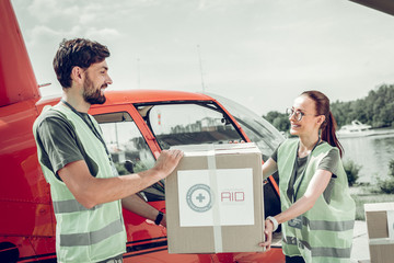 Bearded humanitarian worker helping his colleague holding heavy box