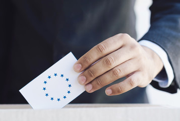 Man putting an european election ballot in a box close-up