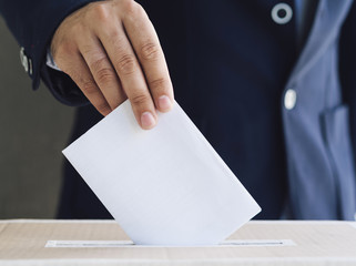 Front view man putting an empty ballot in election box