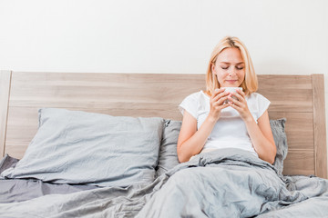 Woman sitting on bed drinking coffee