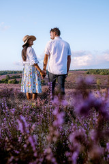 young couple visiting the blooming Heather field Posbank Veluwezoom in the Netherlands, purpple hills with blooming flowers