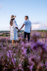 young couple visiting the blooming Heather field Posbank Veluwezoom in the Netherlands, purpple hills with blooming flowers