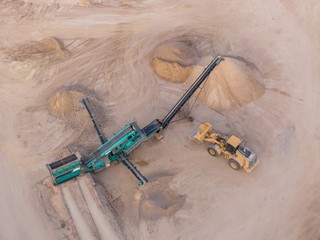 aerial view of a quarry with conveyor belt and wheel loader - stones and sands for construction - top view , open pit mine, extractive industry