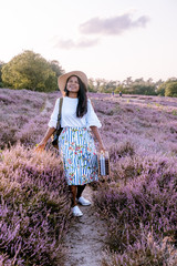 young girl with dress and hat visiting the blooming Heather field Posbank Veluwezoom in the Netherlands, purpple hills with blooming flowers