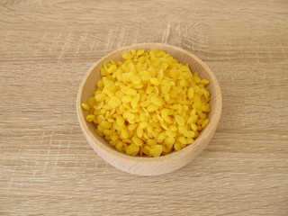 Pure beeswax pastilles in a wooden bowl for natural cosmetics, candles or beeswraps