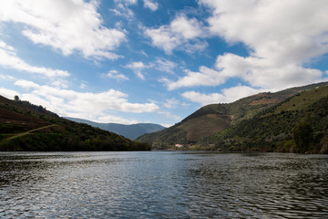 Scenic view of the Douro River with a traditional rabelo boat and terraced vineyards near the Tua village, in Portugal.