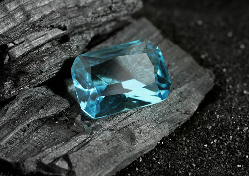 faceted blue jewelry gemstone aquamarine on black coal background