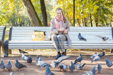 Pretty woman resting in park and feeding pigeons