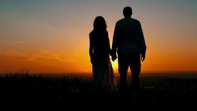 silhouette of couple in love at sunrise man and woman holding hand standing on the hill enjoy beautiful landscape sky with rising sun