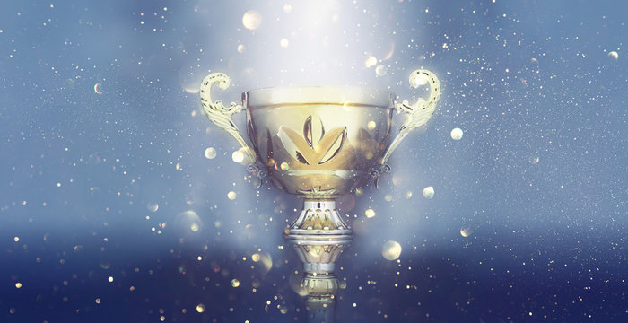 sports concept low key image of gold trophy over dark smoky background and glitter lights