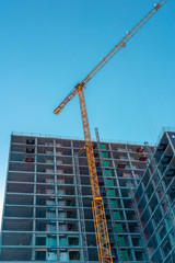 Tall building in construction. Construction site and cranes. Unfinished residential building.