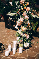 Wedding decor, candles in glass flasks. Festive table decorated with garland of branches and flowers on the center, candles. candles floating in stemware and roses for wedding reception