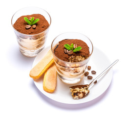 Classic tiramisu dessert in a glass cup on the plate on white background with clipping path