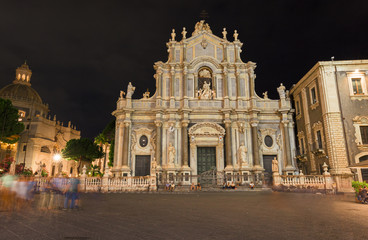 Fototapeta na wymiar Night view of the crowded Duomo Square, with the baroque facade of the Cathedral of S. Agata in Catania in Sicily, Italy.