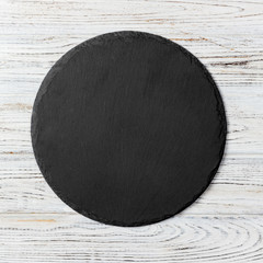 Black round plate on wooden background, top view, copy space