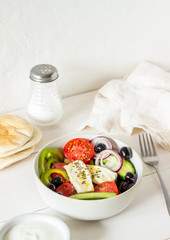 Greek salad on a white wooden background. Tomatoes, peppers, olives, cheese, onions. Healthy eating. Diet. Vegetarian food.