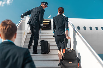 Mature Caucasian pilot looking at flight attendant on plane ladder