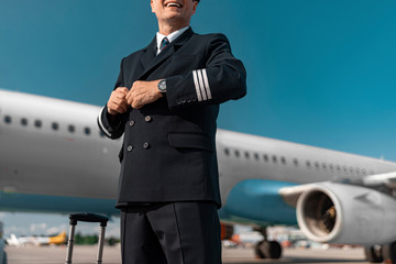 Caucasian pilot buttons his jacket in airport © Yakobchuk Olena