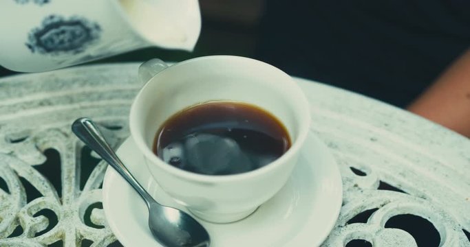 Close up on milk being poured into cup of coffee