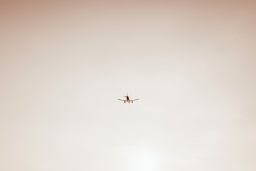 Airplane flying in the sky at sunset. Travel, vacation and holiday concept. Vintage and retro tones with warm beige colors filter. Minimalistic background.