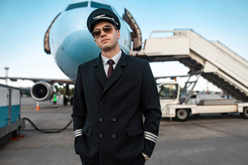 Serious male pilot in uniform waiting for flight in airport