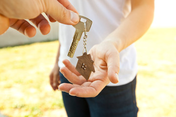 Man giving the metal key from door with wooden trinket in shape of house to the woman