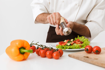 Chef isolated over white wall background in uniform cooking with fresh vegetables.