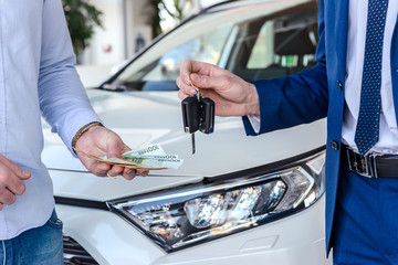 Handshake of two businessmen when selling a car in a motor show, close-up
