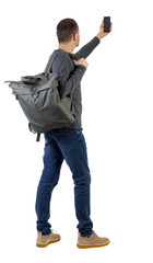 Fototapeta premium Back view of man with bag who makes selfie with a smartphone.