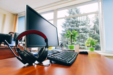 Work place near the window. Place in office with computer monitor, keyboard, headphones and cup of...