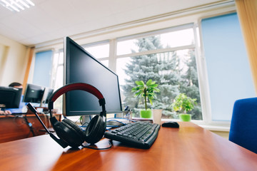 Work place near the window. Place in office with computer monitor, keyboard, headphones and cup of...