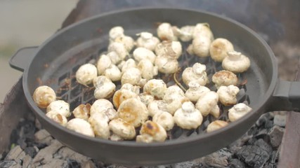 Mushrooms are fried in a special frying pan for mushrooms on coals in nature.