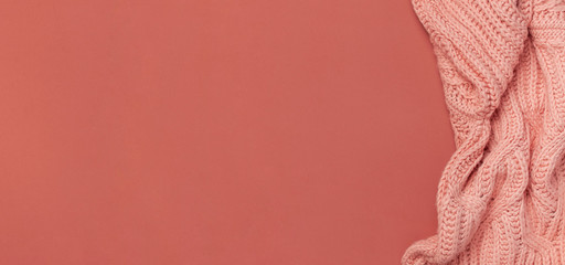 Flat lay autumn composition. Knitted woolen pink female sweater or plaid on burgundy brown background top view copy space. Fall concept. Fashion color, fashionable cozy autumn thing, clothes