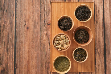 assortment of dry tea in white bowls on wooden surface